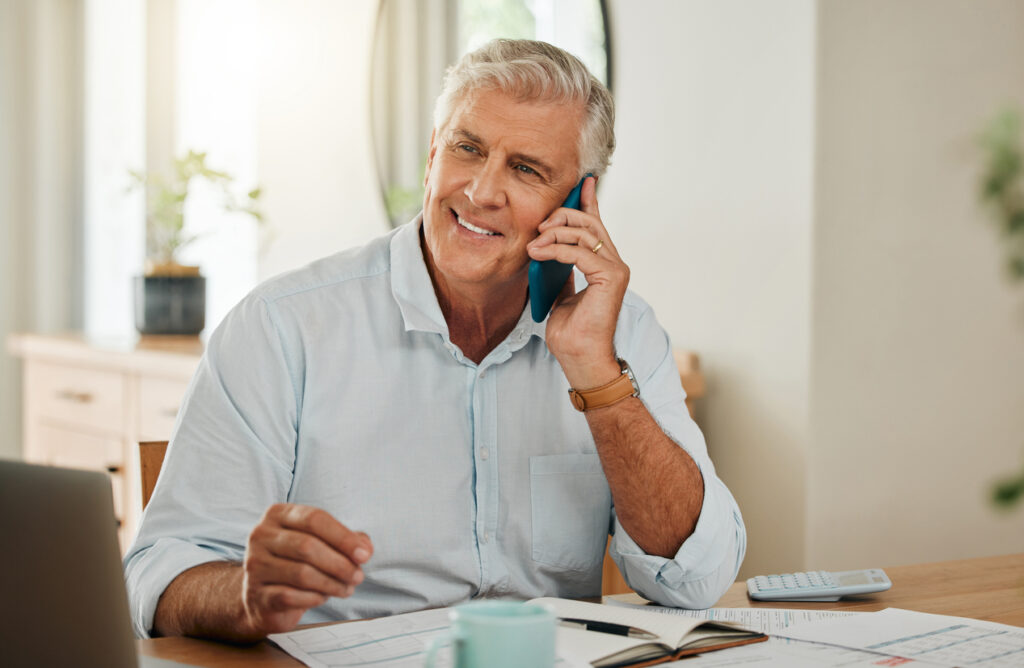 happy elderly man with phone call laptop or communication for home budget consulting financial advisor or planning savings in living room investment or insurance with mobile or smartphone admin